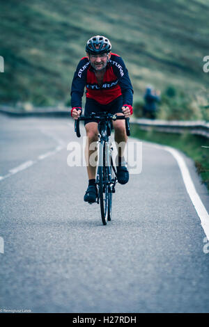 Speeding professionally dressed cyclists on the asphalt during the competition in Scotland Stock Photo