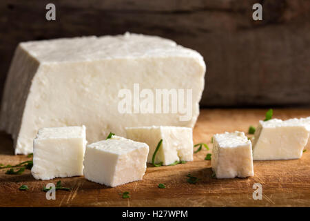 Feta cheese cubes and herbs on a wooden rustic background Stock Photo