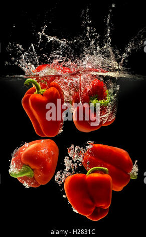 Group of bell pepper falling in water on black Stock Photo