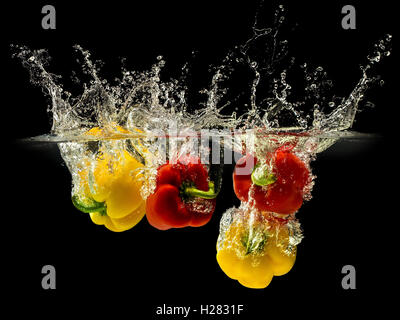 Group of bell pepper falling in water on black Stock Photo