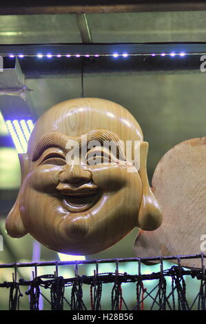 Nha Trang, Vietnam - February 6, 2016: Wooden sculpture of Maitreya Buddha faces are for sale in a local market in Vietnam Stock Photo