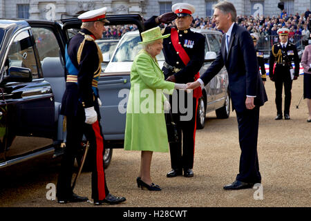 Queen Elizabeth II of Great Britain is greeted by Foreign Secretary Philip Hammond as she arrives at the Royal Marine Beating Retreat music spectacular at the Horse Guards Parade grounds June 4, 2014 in London, England. Stock Photo