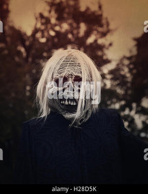 A white scary ghost zombie is outside at night with trees in the background for a decoration or halloween concept. Stock Photo