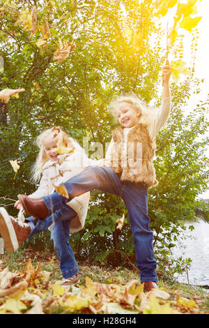 Two children playing and dancing in autumn with leaves Stock Photo