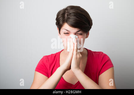 Young woman blowing her nose too hard