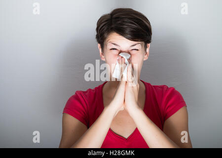 Young woman blowing her nose too hard
