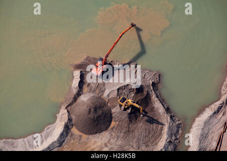 aerial view of two diggers working next to a lagoon in a quarry in Yorkshire, UK Stock Photo