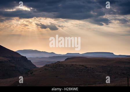 Dramatic sky, storm clouds and sun rays glowing over valleys, canyons and table mountains of the majestic Golden Gate Highlands Stock Photo