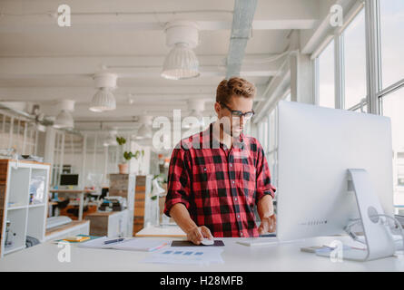 Young man working on computer. Caucasian male office worker using desktop pc in modern office. Stock Photo