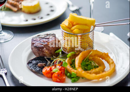 A fillet steak with onion rings and chips Stock Photo