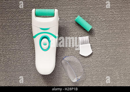Top view of plastic electric foot file and accessories on a gray textured background Stock Photo