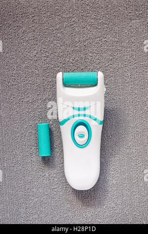 Top view of plastic electric foot file and replacement roller on a gray textured background Stock Photo