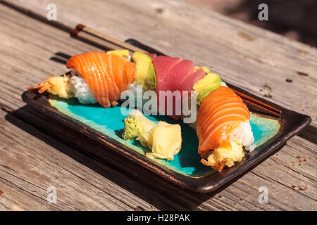 Dragon roll sushi with salmon, tuna, avocado, shrimp tempura and rice on a plate with chopsticks Stock Photo