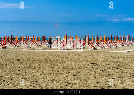 Empty orange deckchairs and sunshades on beach, early season, Viareggio, Tuscany, Italy Stock Photo