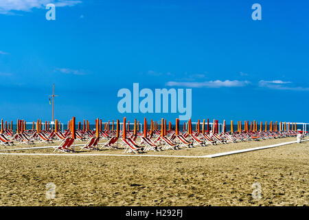 Empty orange deckchairs and sunshades on beach, early season, Viareggio, Tuscany, Italy Stock Photo