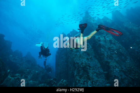 Group of scuba divers exploring sea bottom. Underwater life with beautiful rocks and coral Stock Photo