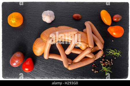 tasty delicious boiled sausages, red, yellow tomatoes, garlic, peppers and rosemary on slate background, close up Stock Photo