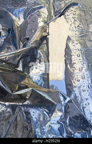 Black plastic cover with raindrops reflecting blue sky. Stock Photo