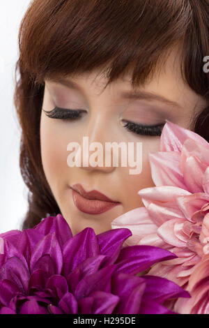 Auburn brunette english rose female close up portrait, eyes closed with huge purple and pink flowers Stock Photo