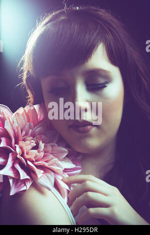 Auburn brunette english rose female portrait, light flare, wearing white jumpsuit with pink flower Stock Photo