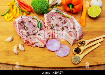 Perfect Raw Pork Neck with Spices, Ripe Tomatoes, Red Onion and Fresh Basil Leaves closeup on Wooden Cutting Board. Top View Stock Photo