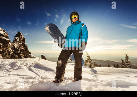 Snowboarder posing on blue sky backdrop in mountains Stock Photo