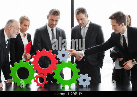 Business people assembling cogwheels, teamwork concept Stock Photo