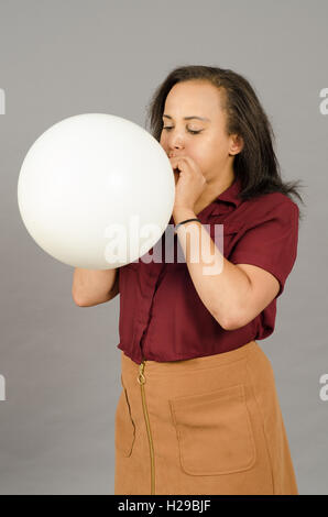 Adult woman blowing up a huge white balloon Stock Photo