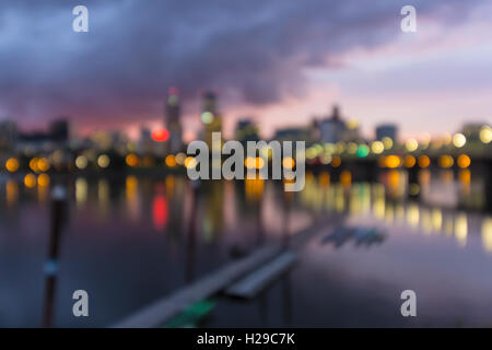 Portland Oregon city downtown waterfront skyline along Willamette River after sunset at dusk out of focus blurred bokeh lights Stock Photo