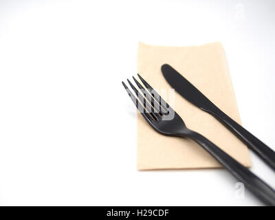 Black plastic fork and knife place on a recycle napkin paper and focus around top area on the fork and knife and blur out other Stock Photo