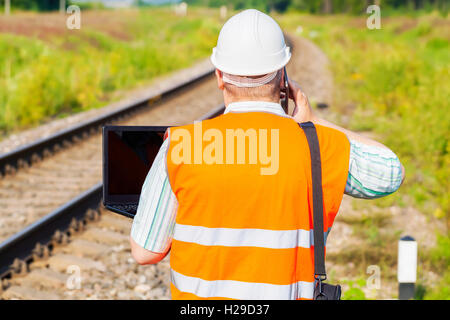 Railway Engineer using smartphone and laptop on railway Stock Photo
