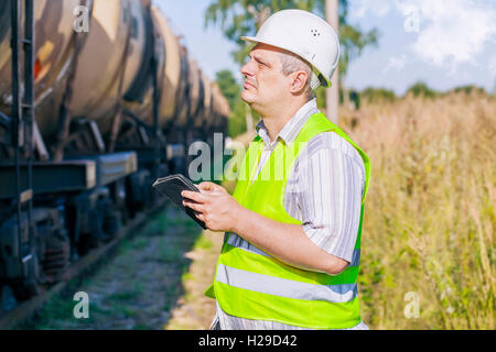 Railway Engineer using tablet PC on railway near freight wagons Stock Photo