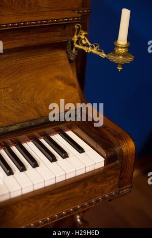 A portion of an antique piano with a candle and holder attached. Stock Photo
