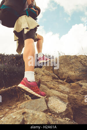 Female hiker walking by the road through countryside, rear view of ...