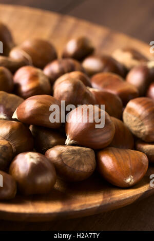 Chestnuts on wooden plate, photographed with natural light (Selective Focus, Focus one third into the chestnuts) Stock Photo