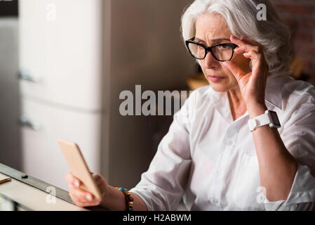 Old lady is being worried receiving new message on her phone Stock Photo