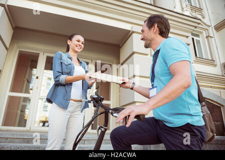 Positive professional courier delivering post Stock Photo
