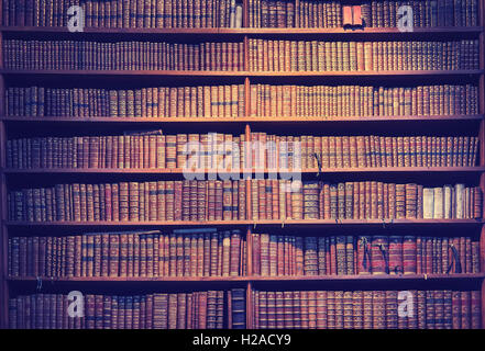 Vintage toned old books on wooden shelves, wisdom concept background. Stock Photo