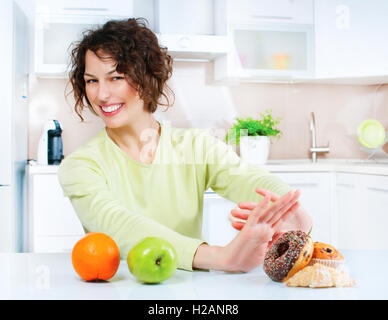 Dieting concept. Young Woman choosing between Fruits and Sweets Stock Photo