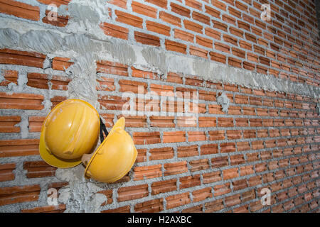 brick wall with yellow safety helmet Stock Photo