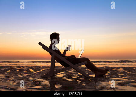 Freelancer sending emails with laptop on tropical beach while traveling Stock Photo