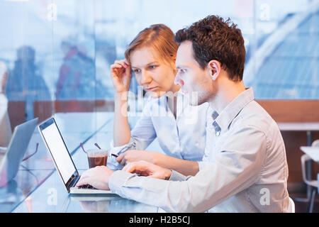 Teamwork, business people looking at the screen of laptop during coffee break in modern cafe interior Stock Photo