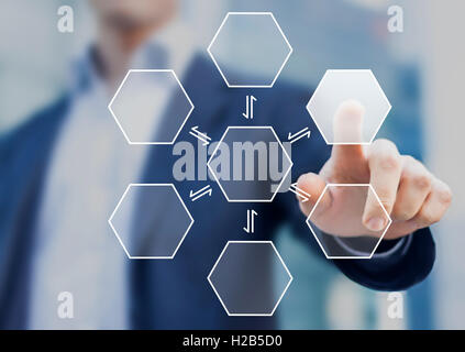 Businessman pushing a virtual hexagonal button with office buildings in background Stock Photo