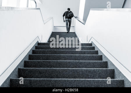 Colorized picture of one man walking upstairs on staircase indoors Stock Photo