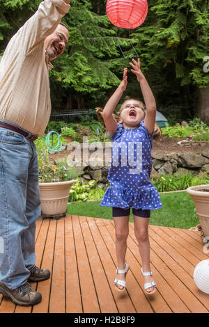Three year old girl playing with a paper lantern with her grandfather in Issaquah, Washington, USA Stock Photo