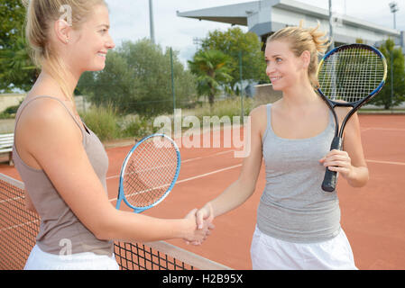 Tennis players shaking hands over net Stock Photo