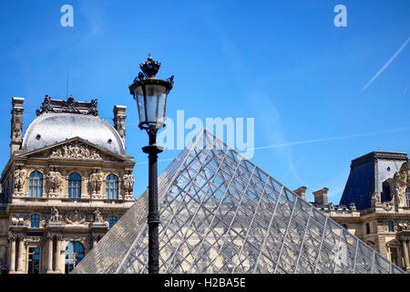 Street lamp in front of famous glass pyramid at courtyard of Louvre Museum in Paris. Stock Photo