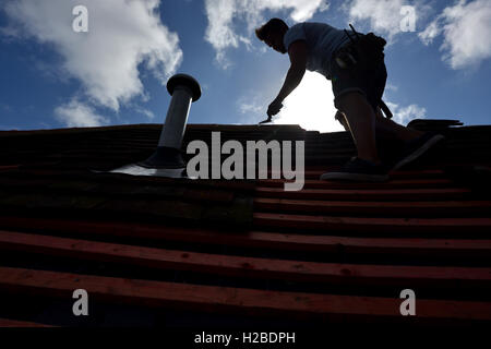 Silhouette of a roofer mending a roof Stock Photo