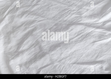 Crumpled white cotton sheets texture, top view of wrinkles on an untidy bed. Stock Photo