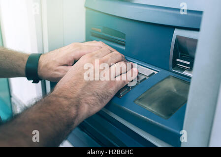 Hands typing PIN at ATM machine for cash money withdrawal Stock Photo